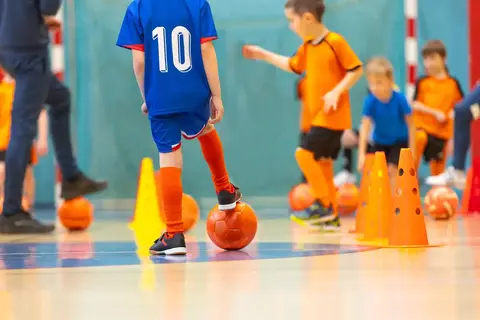 Barn spiller fotball i en gymtime 